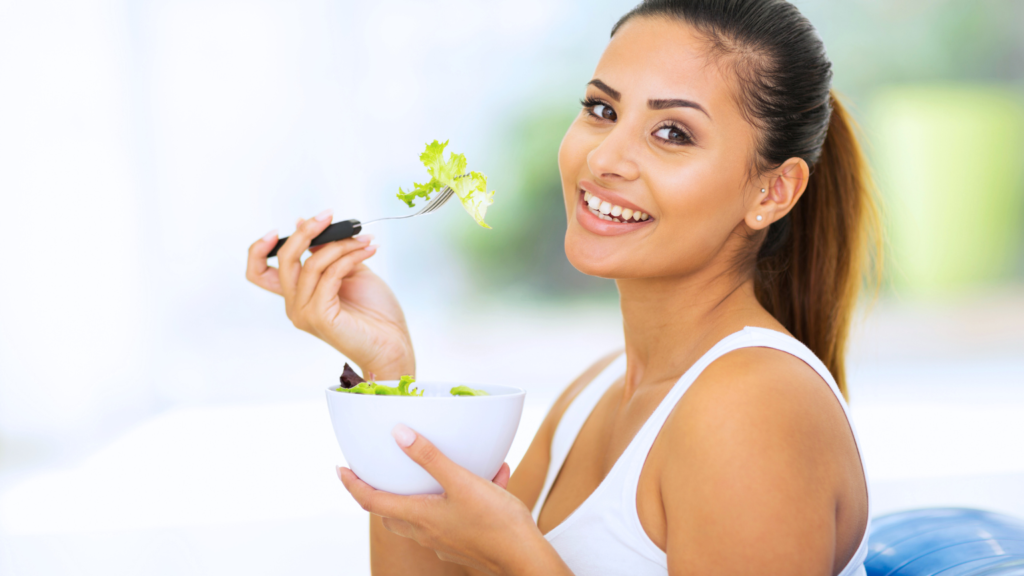 Smiling woman enjoying a healthy salad, promoting overall wellness and dental health at Professional Dental, Utah